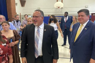 U.S. Education Secretary Miguel Cardona, left, and Illinois Gov. J.B. Pritzker, right, visit Fairview Elementary School in Springfield, Ill., on Wednesday, Sept. 6, 2023, interacting with students in the district's after-school program. Cardona is on a five-state Midwestern bus tour to tout the Biden administration's 